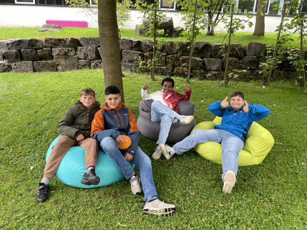 Vier Jugendliche sitzen auf Sitzsäcken auf einer Wiese