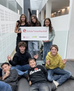 Sieben Jugendliche halten ein Schild auf dem "Schüler*innenHaushalt" geschrieben steht